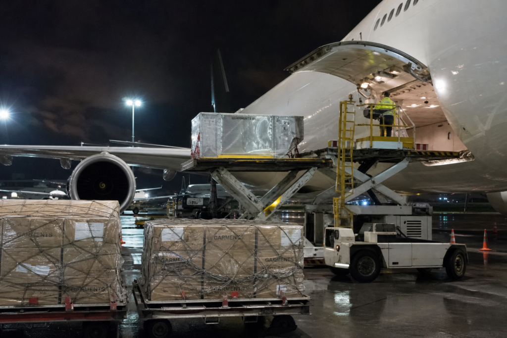 Cargo airplane being loaded with pallets of clothing cartons at an airport cargo terminal to represent air freight for urgent apparel orders